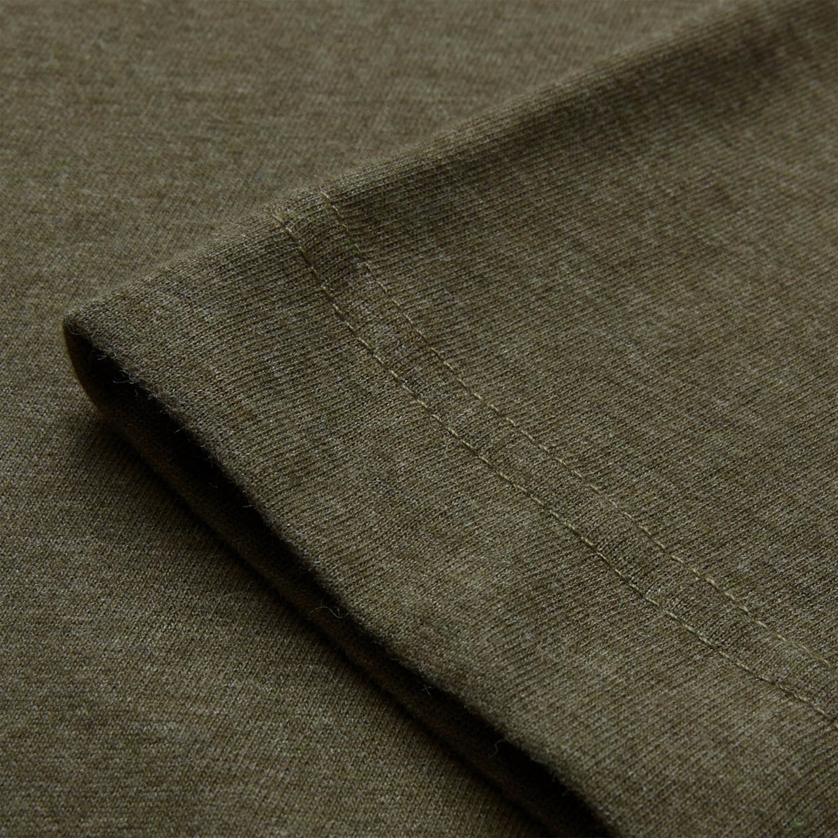 Close-up of a folded sleeve of the Canterbury Tempo+ GFX Training T-Shirt in olive green, highlighting the fabric texture and double-stitched seam.