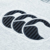 Close-up of the gray fabric on the Women Rakaia 2.0 Hoodie by Canterbury, showcasing a black, textured Canterbury logo with three overlapping stylized C’s.