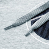 Close-up of two light gray shoelaces lying on heather gray fabric with a partial dark blue circular graphic, as featured on the Women Rakaia 2.0 Hoodie by Canterbury—a classic women’s rugby hoodie offering both comfort and style from Canterbury.