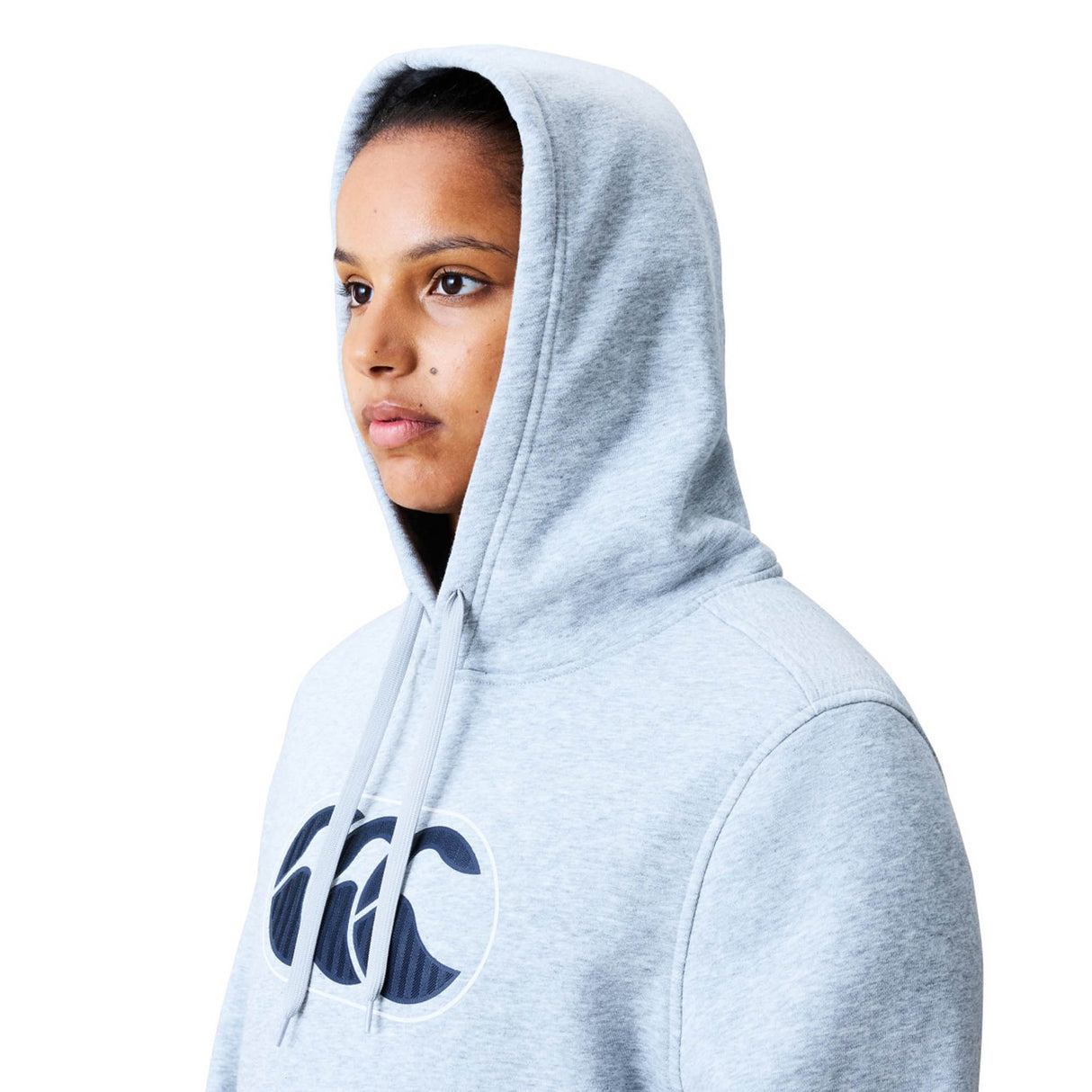 A person is wearing the Women Rakaia 2.0 Hoodie by Canterbury in light gray, featuring a black and white Canterbury logo, and is facing slightly to the side against a plain white background.