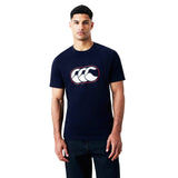A man stands against a plain white background wearing a navy Canterbury Rakaia 2.0 T-shirt, featuring a white and red graphic logo on the chest and paired with dark jeans, embodying signature Canterbury New Zealand rugby apparel style.