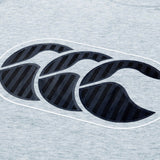 Close-up of a gray fabric from the Canterbury Rakaia 2.0 T-shirt, featuring a prominent dark blue Canterbury logo with three overlapping stylized C shapes—a hallmark of authentic New Zealand rugby apparel.