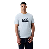 A man wearing a light gray Canterbury Rakaia 2.0 T-shirt featuring a bold black graphic logo on the chest stands against a plain white background, exemplifying classic Canterbury rugby apparel style.