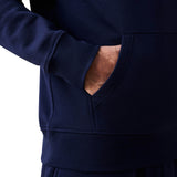 A person wearing a Canterbury Rakaia 2.0 Hoodie in navy blue has their right hand in the front pocket.