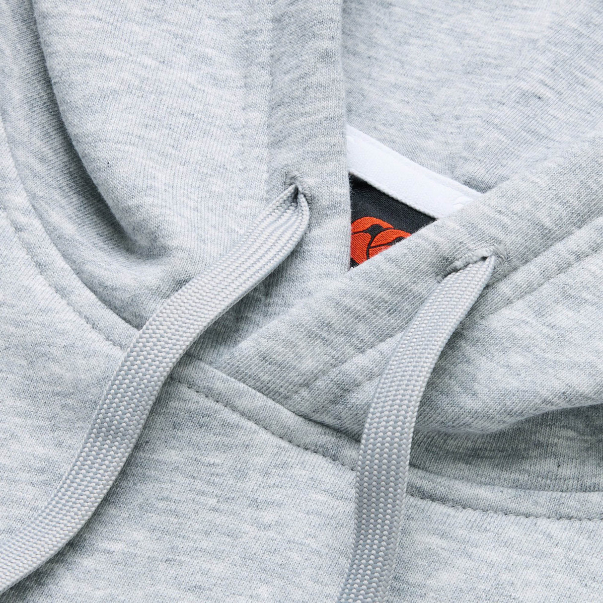 Close-up of the Canterbury Rakaia 2.0 Hoodie in light gray, showcasing its drawstrings and the distinctive red and black Canterbury tag inside the collar.