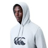 A person wearing a light gray Canterbury Rakaia 2.0 Hoodie with a black and white Canterbury logo on the front looks away from the camera against a plain white background.
