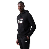 A person wearing a black Canterbury Rakaia 2.0 Hoodie and matching black pants with white Canterbury logos stands facing slightly to the side against a plain white background.