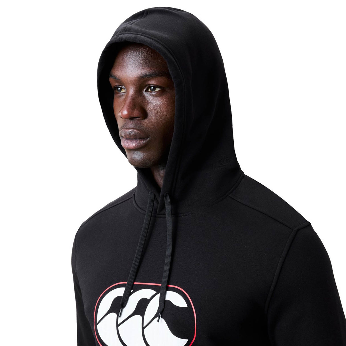 A man wearing the Canterbury Rakaia 2.0 Hoodie in black, featuring a white and red Canterbury logo on the chest, faces slightly to the right.