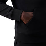 Close-up of a person wearing a black Canterbury Rakaia 2.0 Hoodie with their right hand inside the front pocket, against a plain white background.