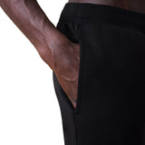 A person wearing black Canterbury Rakaia 2.0 Fleece Pants has their right hand placed inside the side pocket.