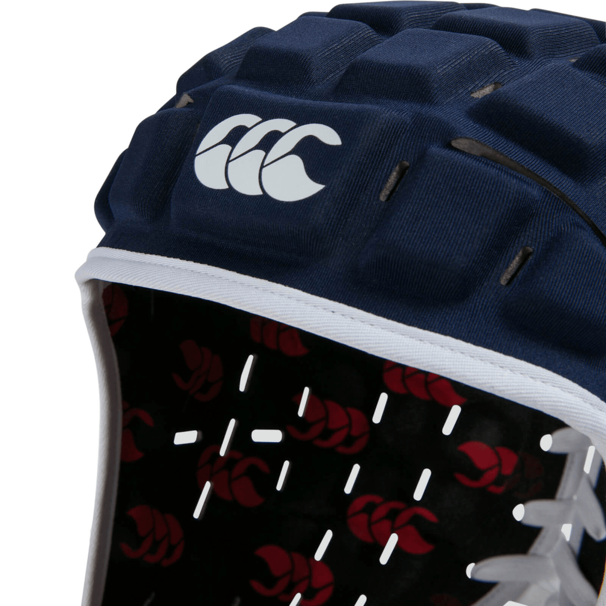 A close-up of the navy blue Canterbury Reinforcer Rugby Headgear Scrum Cap showcases a white logo and trim, alongside a red pattern inside, meeting the World Rugby Specification.