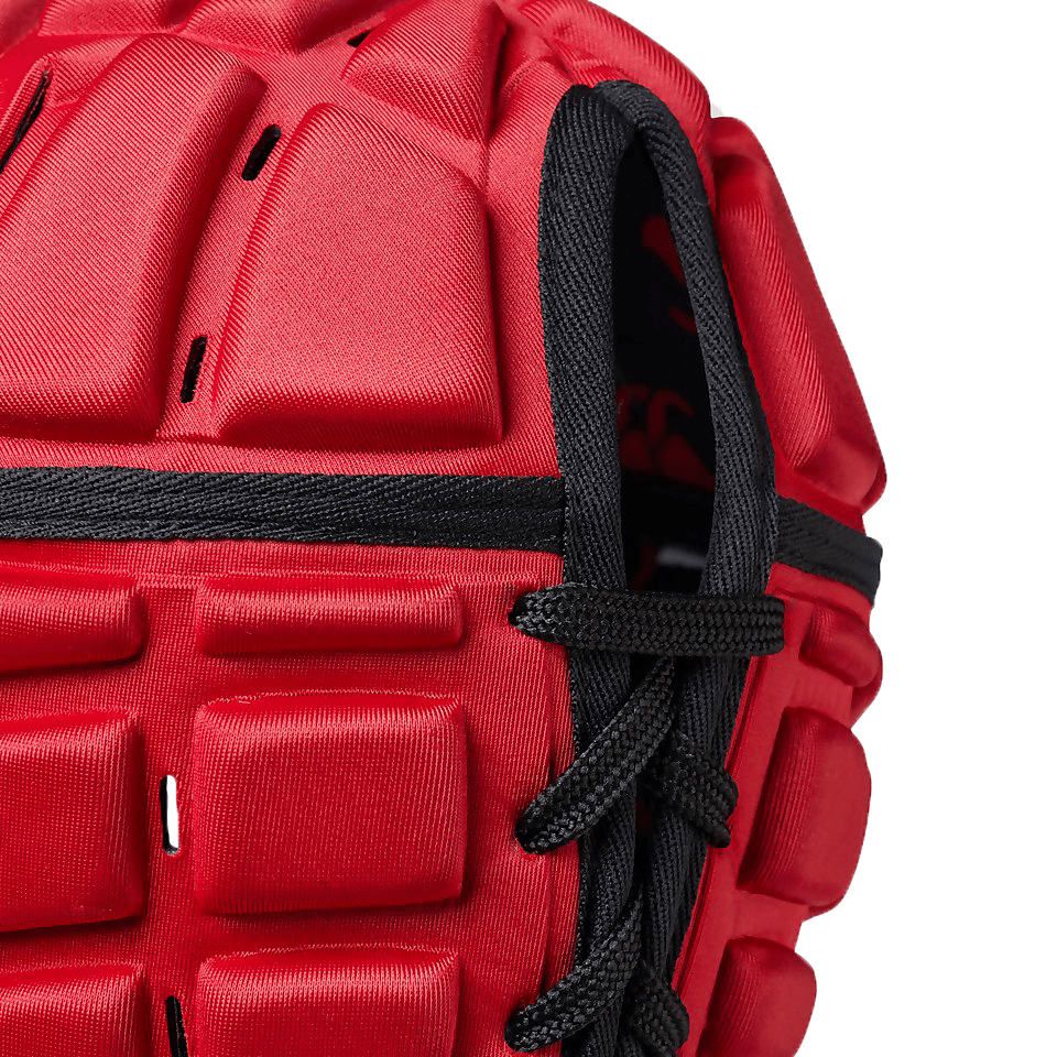 Close-up of a red, textured sports glove with black lacing, featuring Canterbury branding.