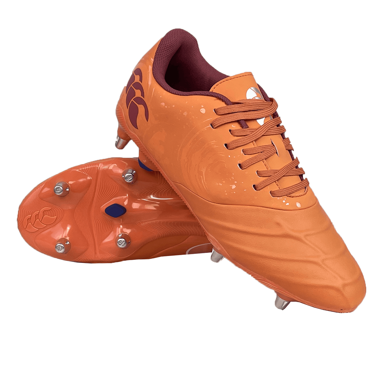 Image of a pair of Canterbury Phoenix Genesis Pro SG soccer cleats in Orange Crush, Amber Yellow, and Mars Dust colorway. The cleats feature laces and metal studs on the soles for ultimate traction. One soft ground boot is placed upright, while the other is positioned sole-up.