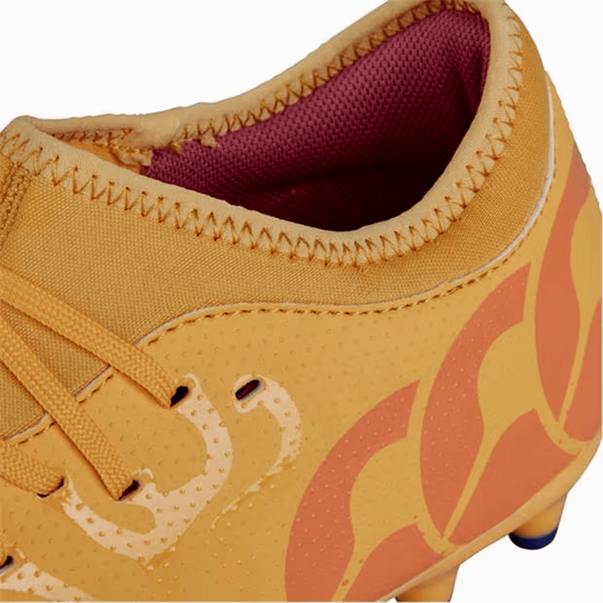 Close-up of the Canterbury Speed Infinite Team FG cleat in Amber Yellow, Orange Crush, and Mars Dust colorway, showcasing an orange exterior with stitched detailing and a pink interior lining. The side features a dynamic yellow and red pattern. Built with a synthetic upper, these cleats deliver the lightweight performance ideal for elite rugby play.