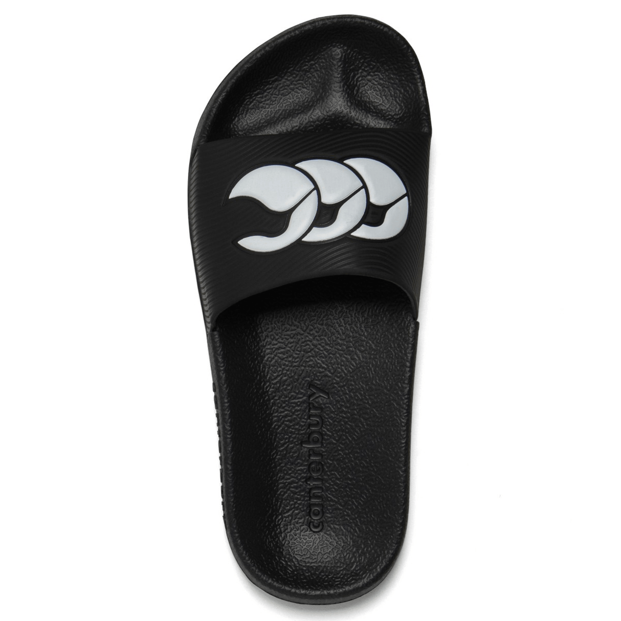A single Canterbury Wide Fit Slide - Black features a textured sole and a white three-leaf logo on the strap. Designed for all-day comfort, the "Canterbury" brand name is imprinted on the footbed, making these perfect shower slides.