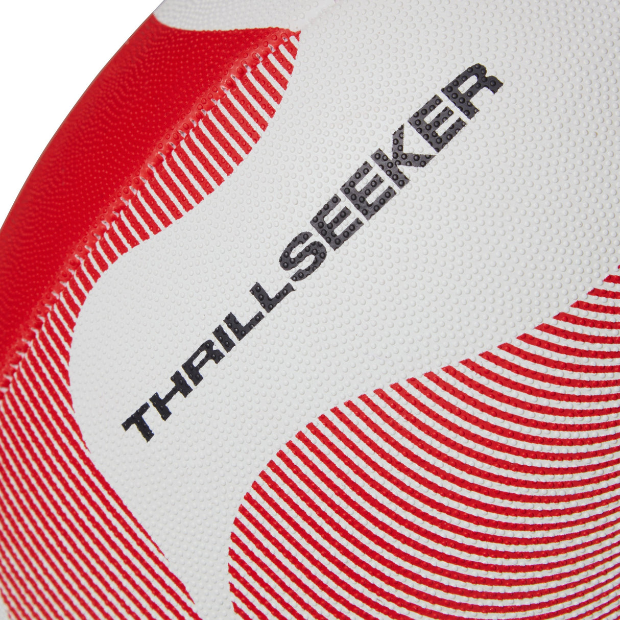 Close-up of a textured Canterbury Thrillseeker Play Rugby Ball with a red and white pattern, displaying the words "thrill seeker" printed in black.