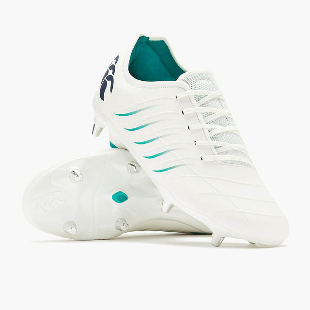A pair of Canterbury Phoenix 2.0 Pro SG rugby boots in WHITE/BALTIC GREEN, featuring white uppers with baltic green accents and metal studs—one shoe standing on its heel, the other lying sole up—set against a plain white background. Ideal for forwards seeking top performance on soft ground.