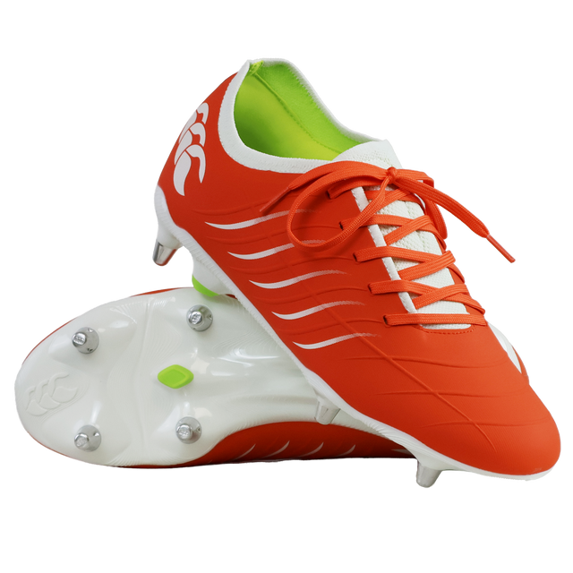 The Canterbury Phoenix 2.0 Pro SG boots in Tangerine Tango/Snow White feature green inner lining; one stands upright, the other lies on its side, displaying metal studs that highlight their durable sports design.