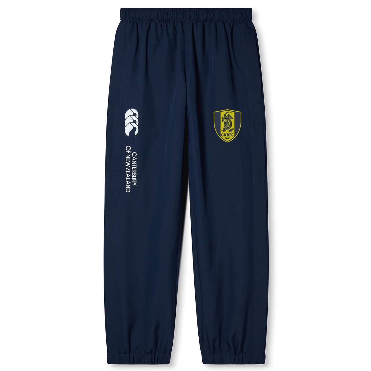 The Gotham Knights Cuffed Hem Stadium Pant by Canterbury, available from EMB Canterbury, are navy blue track pants featuring an elastic waistband and cuffed hem. They boast a logo with a yellow shield and lion on the left leg, as well as "Canterbury of New Zealand" text alongside the Canterbury logo on the right leg. Perfect for rugby enthusiasts.
