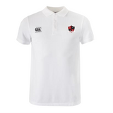 The Southern Pines Youth Rugby Waimak Polo by EMB Canterbury is a white polo shirt with a collar and buttons made from a comfy cotton-polyester blend. It features a black and red shield logo on the left side and Canterbury's iconic logo on the right.