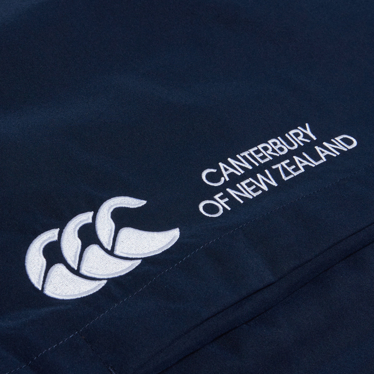Close-up of a navy blue fabric with a white Canterbury logo and "Canterbury of New Zealand" text. Ideal for rugby training, the design features intricate details on the Women's Canterbury Open Hem Stadium Pant.
