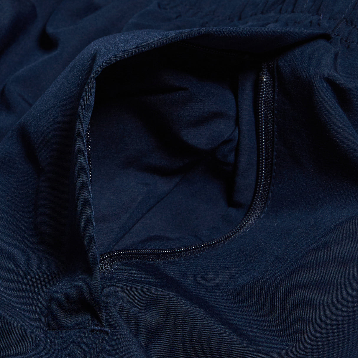 A detailed view of the Women's Canterbury Open Hem Stadium Pant showcases a navy blue fabric with an unzipped pocket, ideal for rugby training. The Canterbury logo adds a touch of authenticity and style to the design.
