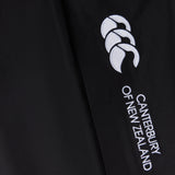 Close-up of black fabric with "Canterbury" branding and a white logo featuring three stylized shapes. The Women's Canterbury Open Hem Stadium Pant is perfect for rugby training, offering full-length leg zips for easy wear and versatility.
