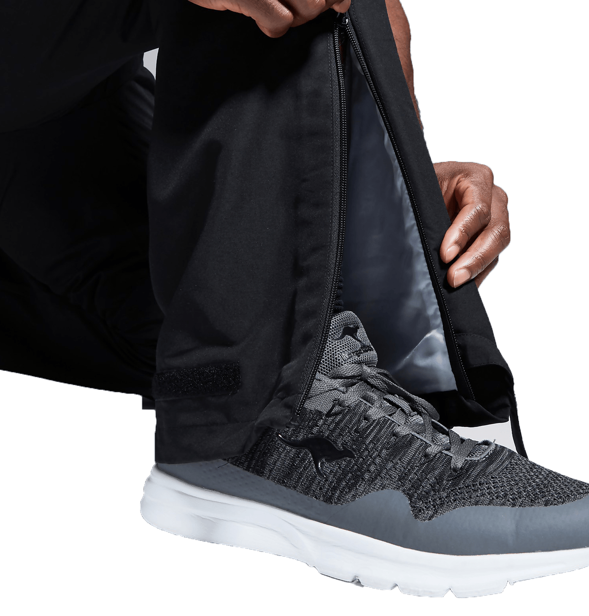 A man holding a pair of Canterbury black and grey sneakers.