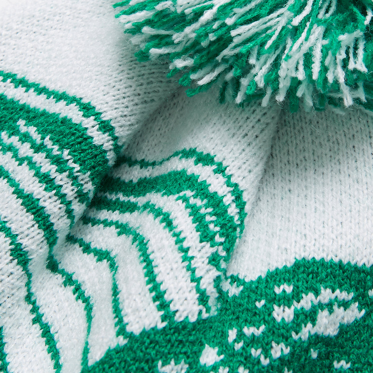 Close-up of the Ireland 26 Bobble Hat by Canterbury in white and green, featuring a pom-pom on top, a striped pattern, and textured stitches.
