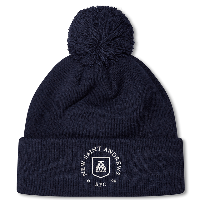 Introducing the New Saint Andrews College Pom Pom Beanie by Canterbury: a navy blue knit beanie with a playful pom-pom on top, featuring the white New Saint Andrews RFC logo embroidered on the cuff. Brought to you by EMB Canterbury.