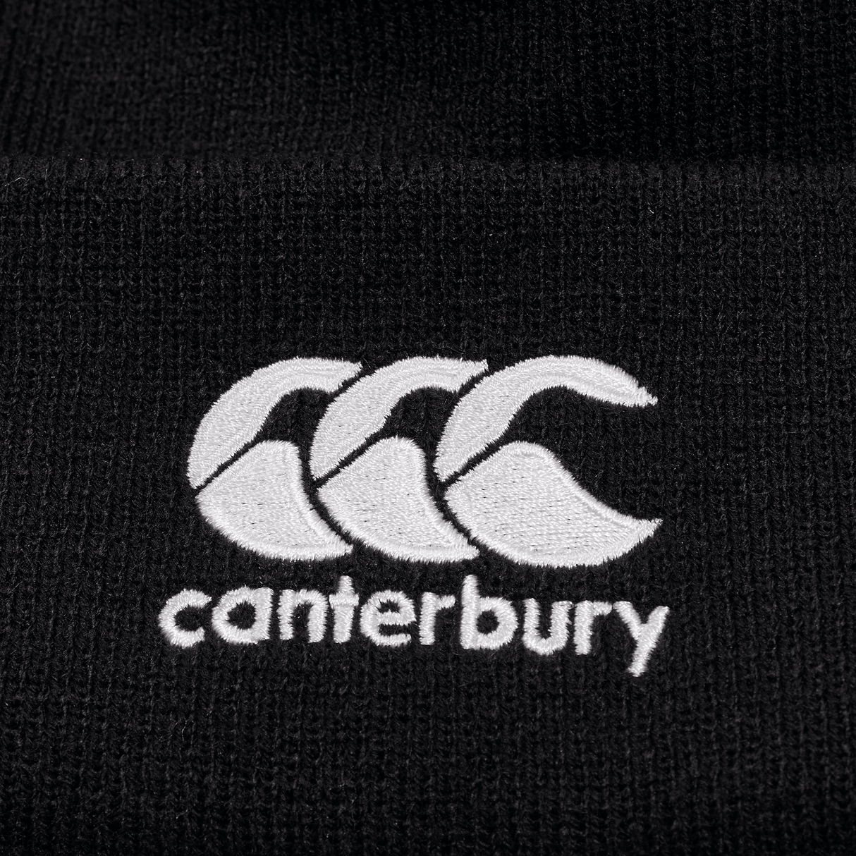 Detail of black knit beanie with white CCC logo on cuff.