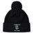 The Amoskeag Rugby Club Pom Pom Beanie by EMB Canterbury is a black knit hat with a folded brim, featuring “AMOSKEAG,” a ram logo, and “Est. 1984” embroidered in white.
