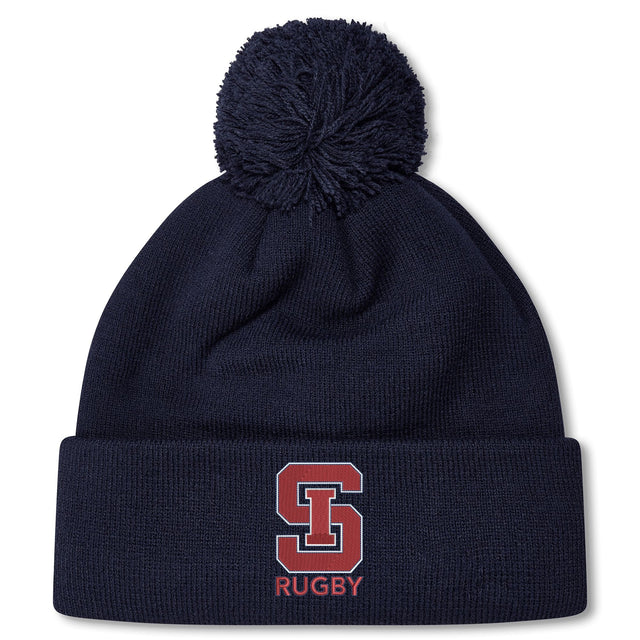 Stay warm in style with the St. Ignatius Rugby Pom Pom Beanie by EMB Canterbury, featuring a navy design, red and white "S" logo, "RUGBY" embroidery on the cuff, soft fleece lining, and playful pom-pom top.