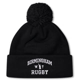 The Birmingham Rugby Text Logo Pom Pom Beanie by Canterbury from EMB Canterbury is a black knit, fleece-lined beanie with a pom-pom on top, featuring “Birmingham Rugby” and a small graphic embroidered in white on the front cuff.