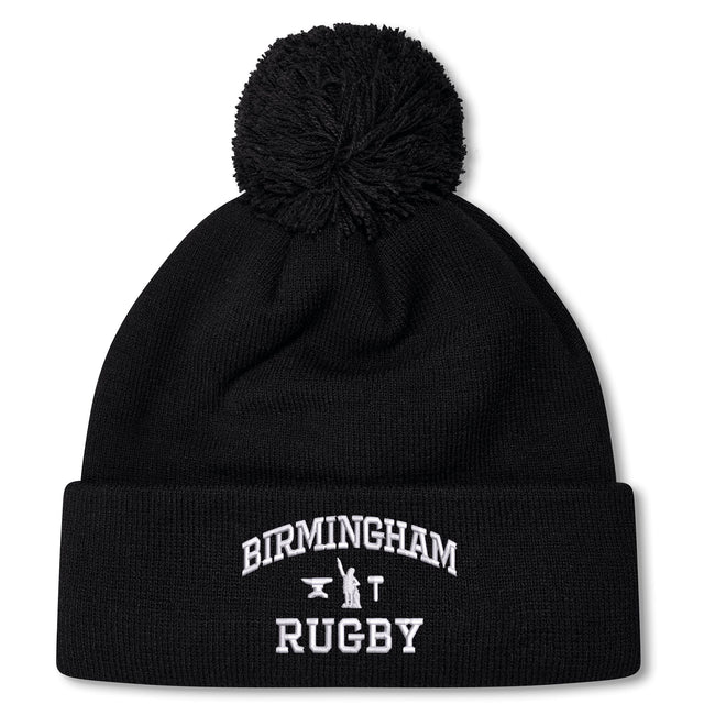 The Birmingham Rugby Text Logo Pom Pom Beanie by Canterbury from EMB Canterbury is a black knit, fleece-lined beanie with a pom-pom on top, featuring “Birmingham Rugby” and a small graphic embroidered in white on the front cuff.