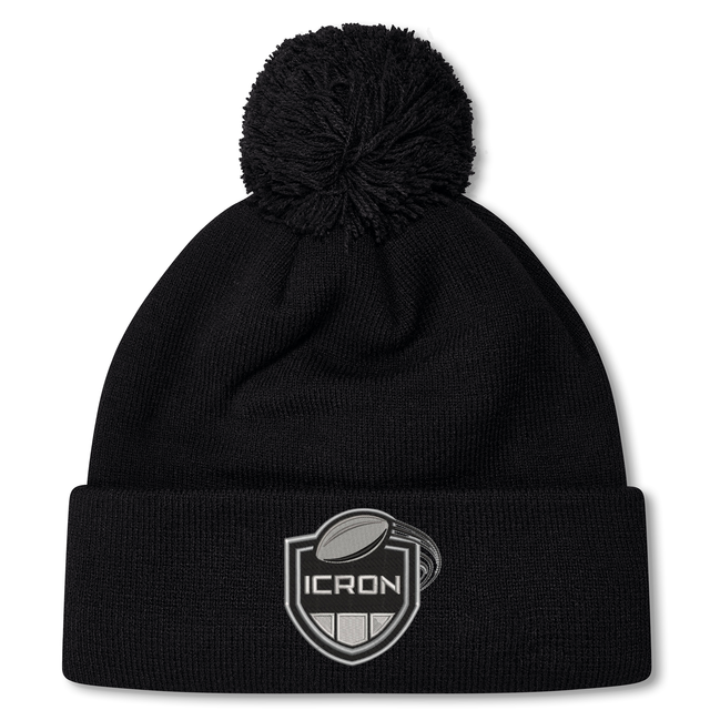 Black ICRON Pom Pom Beanie by Canterbury, featuring a pom pom and a patch with a rugby ball above the word “ICRON.”