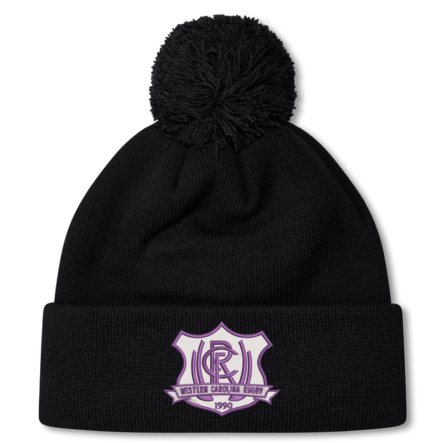 Black knit Western Carolina University Pom Pom Beanie by Canterbury featuring a Western Carolina Rugby emblem on the cuff and a pom-pom topper.