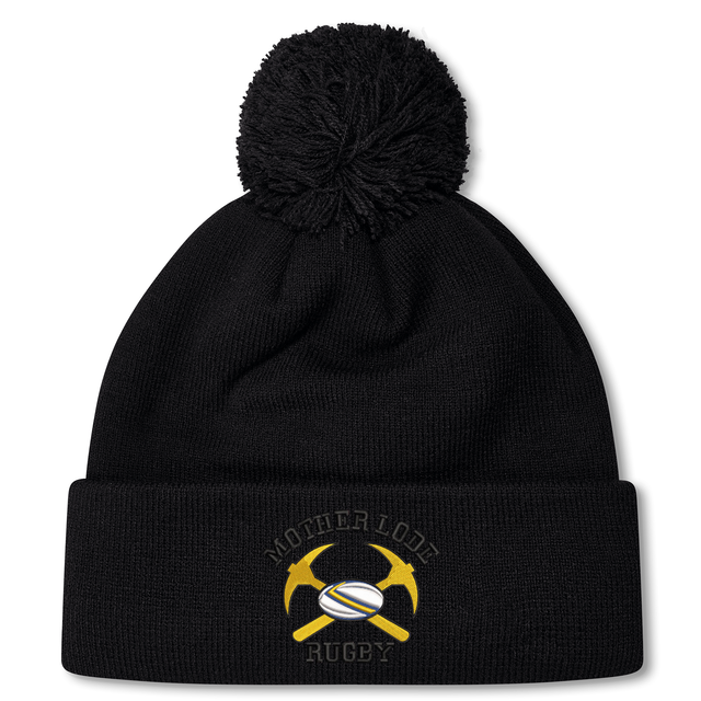 Mother Lode Pom Pom Beanie by Canterbury in black, featuring a pom-pom and an embroidered emblem of crossed yellow pickaxes and a rugby ball.