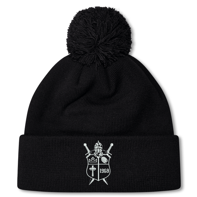 Black fleece-lined Cal Lutheran University Pom Pom Beanie by Canterbury, featuring an embroidered shield emblem with a helmet, swords, a cross, and the year 1969.