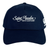 The Saint Anselm College Club Rugby Flexfit Drill Cap by Canterbury features "Saint Anselm Men's Club Rugby" embroidered on the front and a white logo on the side. Brand: EMB Canterbury. Navy blue color.