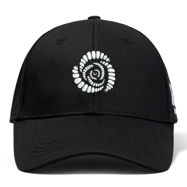 The Missoula All-Maggots Flexfit Drill Cap by EMB Canterbury features a black design with a white spiral pattern of oval shapes and an embroidered logo on the front.