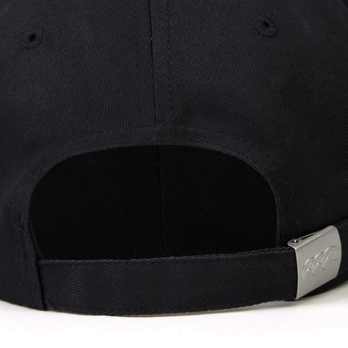 Close-up of the back of a black World Rugby Shop Flexfit Drill Cap by EMB Canterbury showing the adjustable strap and buckle, with a hint of its curved brim.