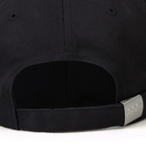 Close-up of the back of a black World Rugby Shop Flexfit Drill Cap by EMB Canterbury showing the adjustable strap and buckle, with a hint of its curved brim.