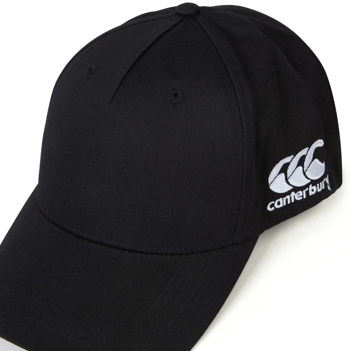 A black World Rugby Shop Flexfit Drill Cap by Canterbury with a curved brim and an embroidered white EMB Canterbury logo on the side.