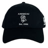 The Amoskeag Rugby Club Flexfit Drill Cap by EMB Canterbury features a black design with a white ram's head logo and "AMOSKEAG Est. 1984" embroidered on the front, offering a stylish custom cap for everyday wear.