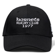The Hornets Rugby Club 1977 Flexfit Drill Cap by Canterbury features black fabric with white embroidered "hornets RUGBY CLUB 1977" text on the front. This curved brim cap from EMB Canterbury also includes a subtle CCC logo, combining style and comfort for rugby fans.