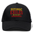 The Potomac Exiles Rugby Club Flexfit Drill Cap by Canterbury from EMB Canterbury features "POTOMAC EXILES RUGBY" embroidered on the front in yellow and red letters, accented with two red stars and horizontal lines beneath the text. This black cap boasts a curved brim and a bold embroidered logo, delivering a distinctive athletic look.