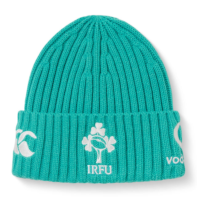 The Ireland 26 Beanie by Canterbury is a teal ribbed knit hat featuring embroidered white logos, including a shamrock rugby emblem and “IRFU” text on the folded brim.