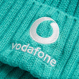 Close-up of a turquoise knitted fabric from the Ireland 26 Beanie by Canterbury, featuring the Vodafone logo and name embroidered in white thread, characteristic of Canterbury’s beanie style.