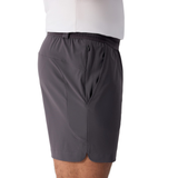 A person shown from the side with hands in pockets, wearing Everest Woven Shorts by Canterbury in gray and a white shirt.